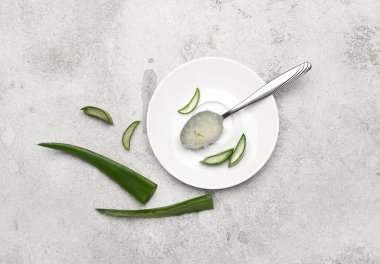 Tabakta aloe jeli kaşık ve açık arkaplanda yapraklar