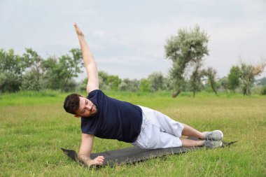 Sportif genç adam parkta paspas üzerinde egzersiz yapıyor.