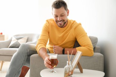Yakışıklı adam evde bira içiyor.