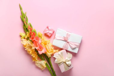 Bir buket güzel gladiolus çiçeği ve renkli arka planda hediye kutuları.