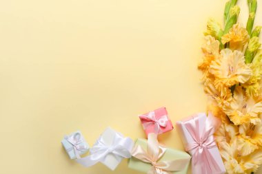 Bir buket güzel gladiolus çiçeği ve renkli arka planda hediye kutuları, yakın plan.