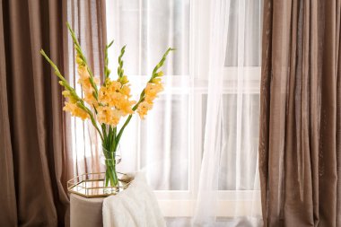 Vase with beautiful gladiolus flowers in interior of room