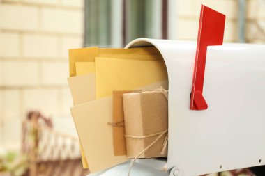 Mektuplarla dolu posta kutusu ve açık hava paketi, yakın plan.