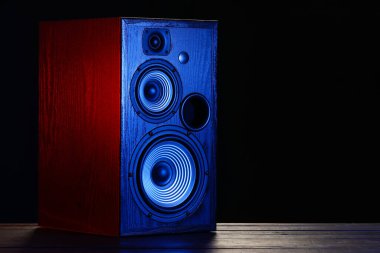 Modern loudspeaker on table against black background