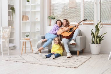 Mutlu genç aile evde gitar çalıyor.