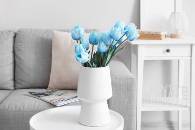 Aydınlık oturma odasındaki masada mavi laleli vazo