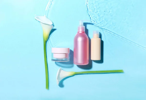Verschiedene Kosmetikprodukte Und Calla Lilien Wasser Auf Blauem Hintergrund — Stockfoto