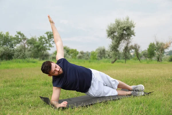 Sportif genç adam parkta paspas üzerinde egzersiz yapıyor.