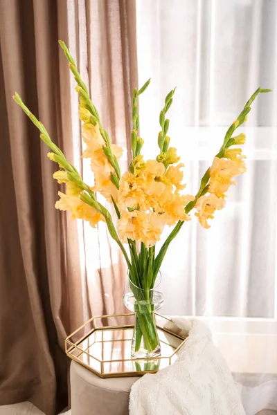 Vase with beautiful gladiolus flowers in interior of room