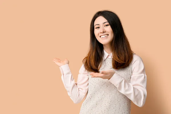 Inviting Young Asian Woman Showing Something Beige Background — Stock Photo, Image