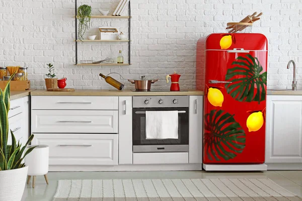 Red refrigerator with print of tropical leaves in interior of modern kitchen