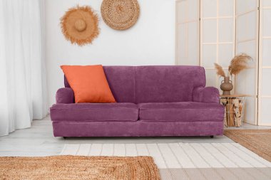 Interior of light living room with sofa and folding screen 