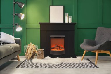 Yeşil duvarın yanında siyah şöminesi, koltuğu, koltuğu ve lambası olan modern oturma odasının içinde.