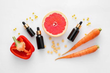 Beyaz arka planda gerekli yağ, hap, greyfurt, dolmalık biber ve havuç şişeleri