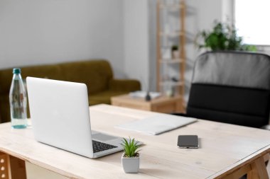 Işık odasında modern dizüstü bilgisayarı ve cep telefonu olan çalışma alanı