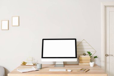 Modern bilgisayar, fincan, gazete ve cep telefonuyla aydınlık duvarın yanında rahat bir iş yeri