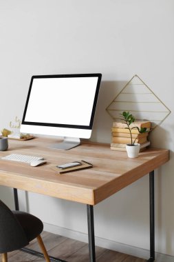 Mobile phone and notebook on wooden table with modern computer near light wall