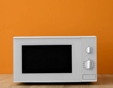 Modern mikrodalga fırın ahşap masada turuncu arka planda