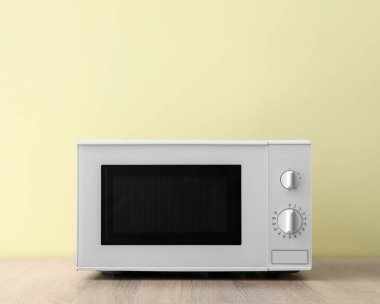 Ahşap masada renk arkaplanına karşı mikrodalga fırın