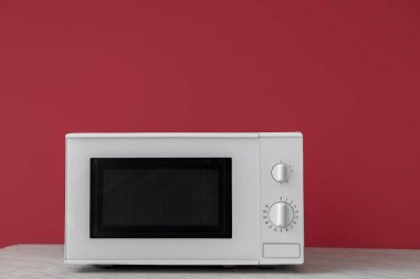 Ahşap masadaki modern mikrodalga fırın renk arkaplanına karşı