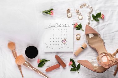 İşaretli tarihi ve beyaz kumaş arka planında gelin aksesuarları olan düğün takvimi