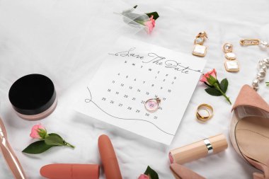 İşaretli tarihi ve beyaz kumaş arka planında gelin aksesuarları olan düğün takvimi