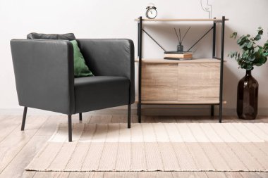 Comfortable armchair, standing desk and stylish carpet in light room