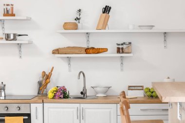 Sink with beautiful flowers near light wall in kitchen