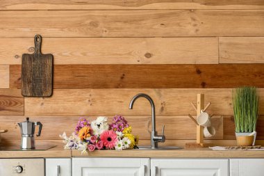 Modern kitchen with bouquet of flowers in sink