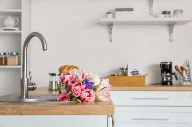 Mutfağın içinde bir buket güzel çiçekle birlikte lavabo.