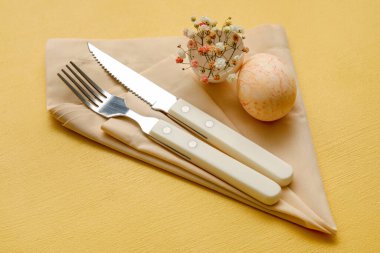 Sarı arka planda çigila çiçekleri olan Paskalya kutlaması için şık bir masa.