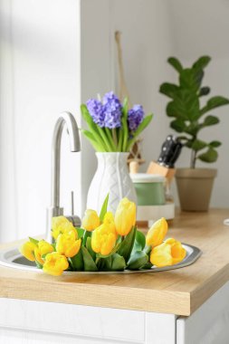 Beyaz duvarın yanında lavaboda bir buket güzel lale.