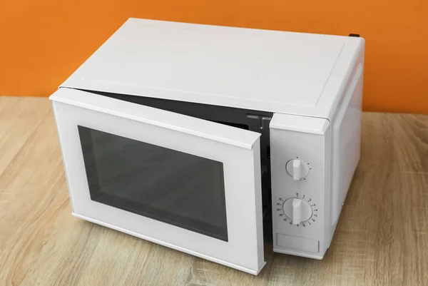 Modern Microwave Oven Opened Door Wooden Table Orange Background — Stockfoto