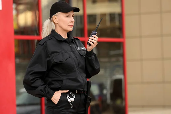 Female security guard with radio transmitter outdoors