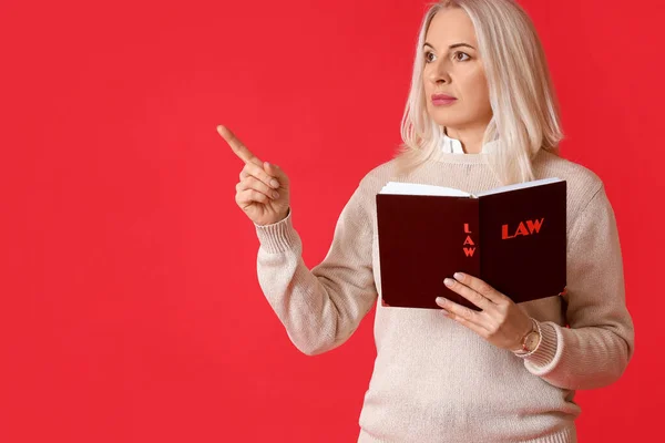 Mature Female Judge Law Book Pointing Something Red Background — Stockfoto