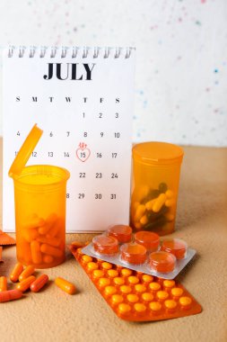 Calendar with marked date for sex and pills on beige table