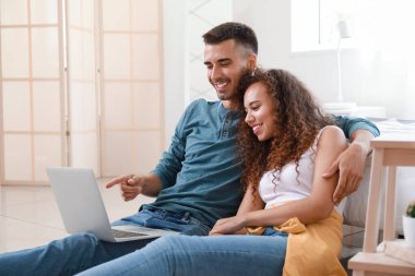Young couple using modern laptop in bedroom