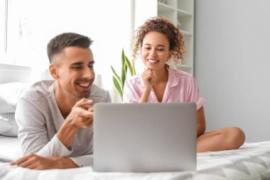 Genç çift yatak odasında dizüstü bilgisayar kullanarak