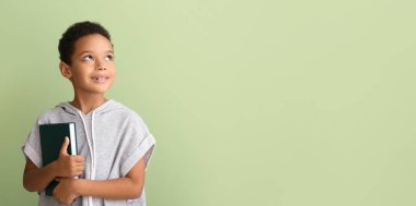 Yeşil arka plan üzerine kitabı olan küçük Afro-Amerikalı çocuk.