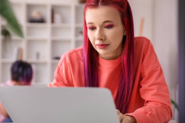 Evde dizüstü bilgisayar kullanan parlak saçlı güzel bir kadın.