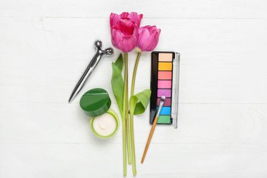 Beyaz ahşap arka planda lale buketi ve kadın aksesuarları.