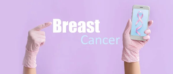 手牵着屏幕上有粉色带子的手机 背对着淡紫色的文本Breast Cancer — 图库照片