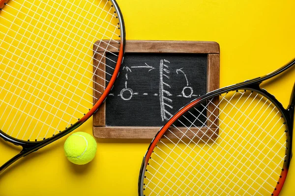 Chalkboard with drawn scheme of tennis game, ball and rackets on yellow background
