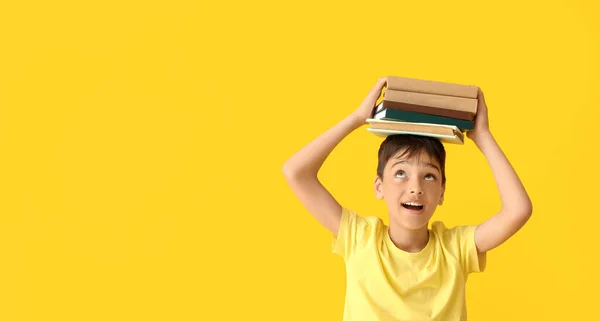 Küçük Çocuk Sarı Arka Planda Bir Yığın Kitap Tutuyor — Stok fotoğraf