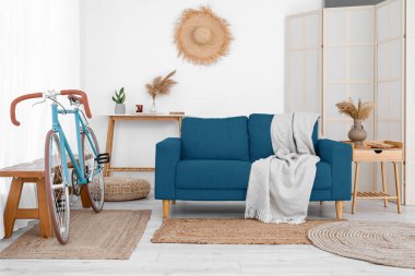 Şık oturma odasında rahat bir kanepe, bisiklet ve katlanabilir ekran. 