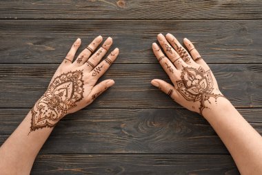 Female hands with beautiful henna tattoo on wooden background