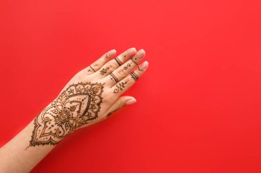 Female hand with beautiful henna tattoo on color background