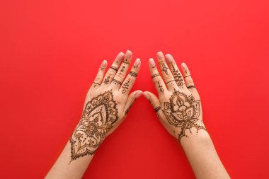 Female hands with beautiful henna tattoo on color background, closeup