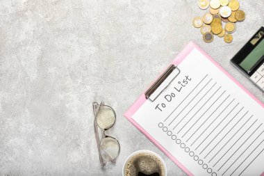 Clipboard with blank to do list, eyeglasses and money on light background
