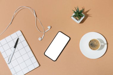 Cep telefonu, defter, kulaklık ve kahve fincanı.